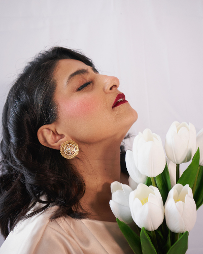 Woman with closed eyes holding white tulips against a light background