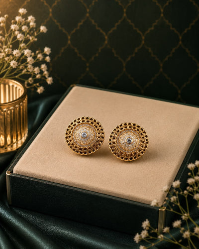 Gold earrings on a beige cushion with a decorative background